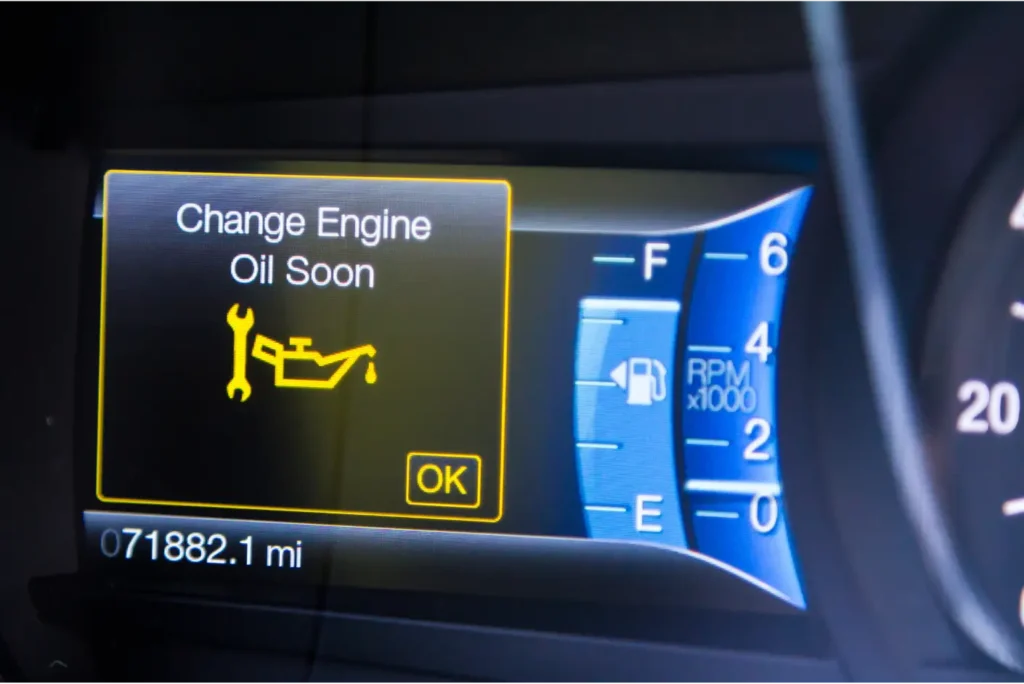 A car dashboard displaying a "Change Engine Oil" warning light.