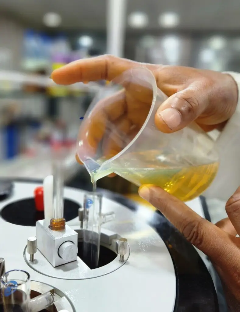 A close-up of a viscometer in the Climax Lubricants lab, with a technician pouring golden engine oil for quality control testing.